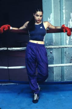 a woman wearing red boxing gloves standing in front of a metal door with her arms stretched out