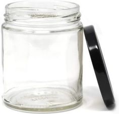 a glass jar with a black lid next to a plastic spoon on a white surface