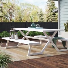 a white table and bench sitting on top of a wooden floor next to a house