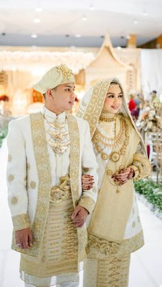 a man and woman dressed in wedding attire standing next to each other on a white floor