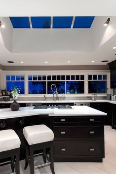 a large kitchen with white counter tops and black cabinets