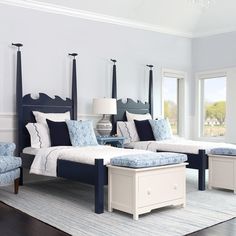 a bedroom with blue and white bedding, two chairs and a ottoman in the middle