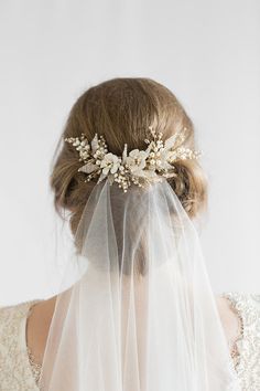 the back of a bride's head wearing a veil with flowers and pearls on it