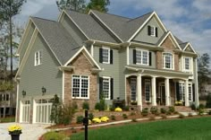 a large gray house with lots of windows and landscaping around the front door is shown