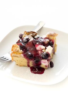 a piece of cake with blueberries and powdered sugar is on a white plate