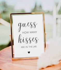 a sign that says guess how many kisses are in the jar on a wooden table