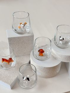 four glass bowls with animals in them on top of a white countertop next to each other