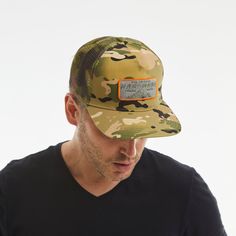 a man wearing a camo hat looking down at his cell phone in front of him