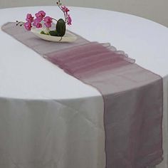 a white table topped with a vase filled with pink flowers