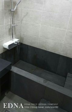 a black and white tiled bathroom with a sink, shower head, and toilet paper dispenser