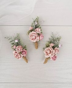 three boutonnieres with pink flowers and greenery