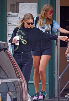 two women are walking down the street with their hands in each other's pockets