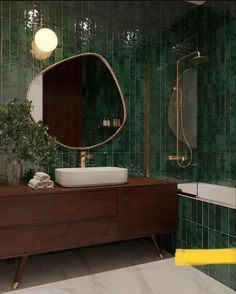 a bathroom with green tiles and a wooden cabinet in front of the mirror that is above the sink