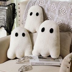 three stuffed ghost pillows sitting on top of a chair