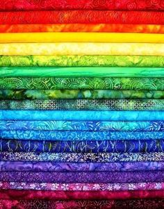 a rainbow colored quilt with many different colors and patterns on the bottom, along with other fabrics