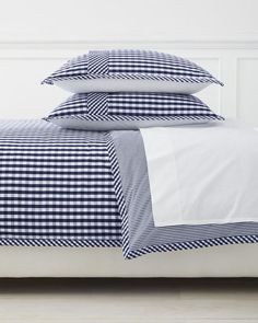 a bed with blue and white gingham comforter on it, next to two pillows