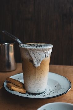 there is a drink on the plate with a spoon in it and some cookies next to it