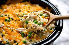 chicken and rice casserole in a black crock pot with a wooden spoon