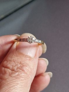 a woman's hand holding a diamond ring