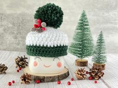 a white and green hat sitting on top of a wooden stump next to pine cones