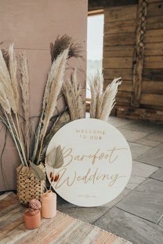 a welcome sign and two vases on the ground next to each other with flowers in them