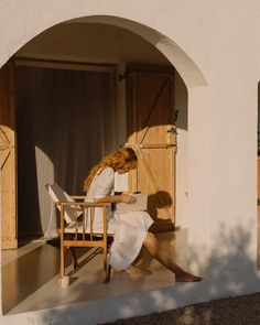 a woman sitting on a chair in front of a doorway