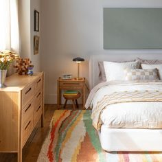 a bedroom with a bed, nightstands and rug on the floor in front of it