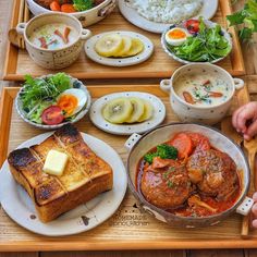 a wooden tray topped with lots of different types of food on top of plates and bowls