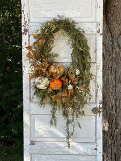 an old door with a wreath and pumpkins on it