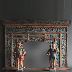 two figurines sitting on top of a table next to a mirror with an ornate frame