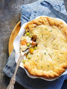 a chicken pot pie on a plate with a fork next to it and a blue napkin