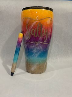 a colorful cup with the word salty written on it and a pen resting next to it