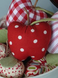 a bowl filled with red and white fabric covered donuts next to a stuffed apple