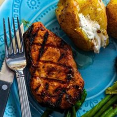 a blue plate topped with meat, potatoes and asparagus next to a fork