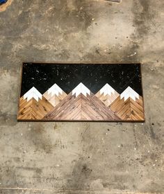 a skateboard is laying on the ground with mountains painted on it