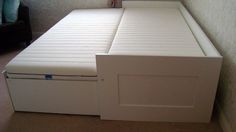 a white bed with drawers underneath it in a room