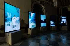 four televisions are on display in a room with black and white checkered flooring