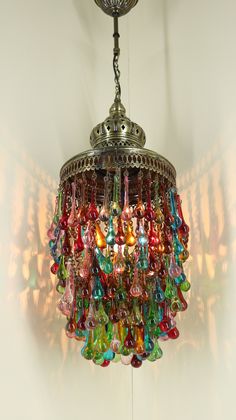 a chandelier hanging from the ceiling with colorful glass beads on it's chain