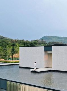 a person standing in front of a building on top of a large body of water