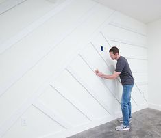 a man standing in front of a white wall holding on to a paneled door