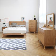 a bed room with a neatly made bed and wooden furniture on the hardwood flooring