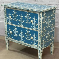 a blue and white painted cabinet with flowers on it