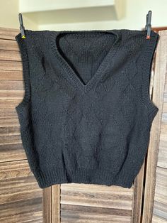 This gorgeous hand knit black wool sweater vest was lovingly created by Georgene Johnson of Hays Kansas. It uses multiple stitches throughout the design. The Unisex sweater vest measures 44 inches wide by 25 inches long.  Care: Dry clean or hand wash cold/gentle cycle. Condition: Very Good Fitted Black Sweater Vest, Winter Knit Black Vest, Black Knit Winter Vest, Black Knit Vest For Winter, Black Fitted Sleeveless Sweater, Fitted Black Sleeveless Sweater, Fitted Sleeveless Black Sweater, Fitted Black Knitted Sweater Vest, Winter Black Knit Vest