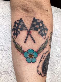 a man's leg with a checkered flag and blue flower tattoo on it