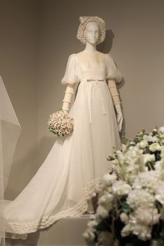 a wedding dress and bouquet on display in a museum