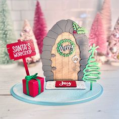 there is a christmas card with a door and presents in front of the sign that says santa's workshop