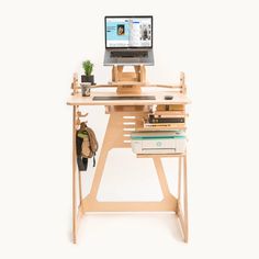 a wooden desk with a computer on top of it next to books and a bag