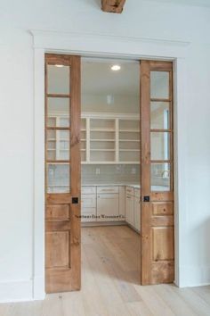 an empty kitchen with wooden doors and white walls