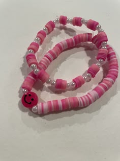 two pink and white bracelets with a smiley face beaded on the end one