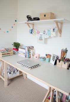 a white desk topped with lots of books next to a shelf filled with pictures and papers